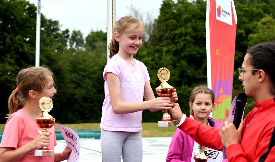 Freudestrahlend nimmt Anastasia Wolf den Siegerpokal aus den H&auml;nden von Florian Wendt, dem stellvertretenden sportlichen Leiter des LAZ Soest entgegen. Die Georg-Sch&uuml;lerin gewann in der Altersklasse 2016 vor Lara Hinkelmann (links, Georg) und Luisa Kruppa (rechts, Bruno). Foto: Bottin
